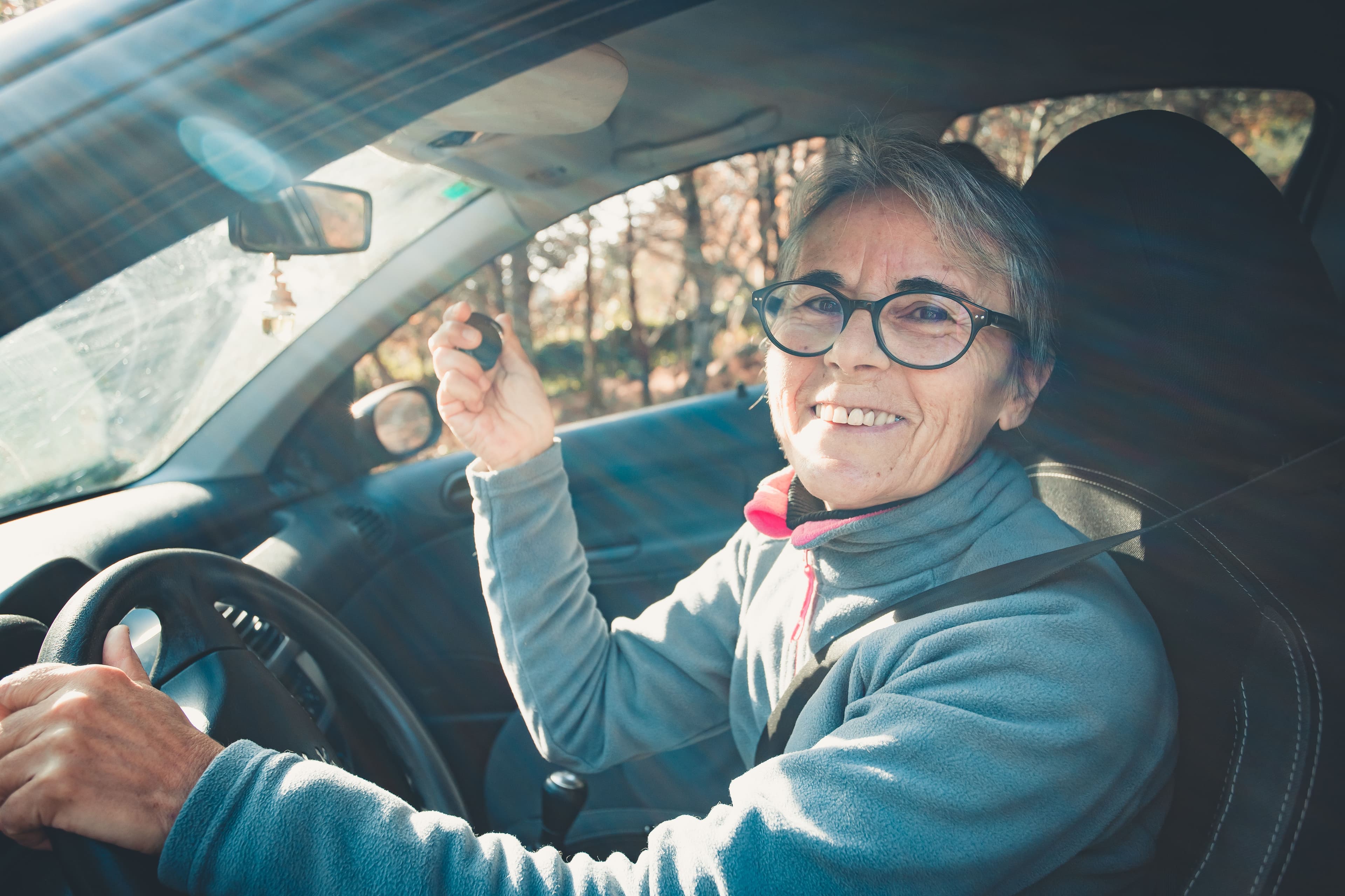 Femme senior dans sa voiture, clé en main